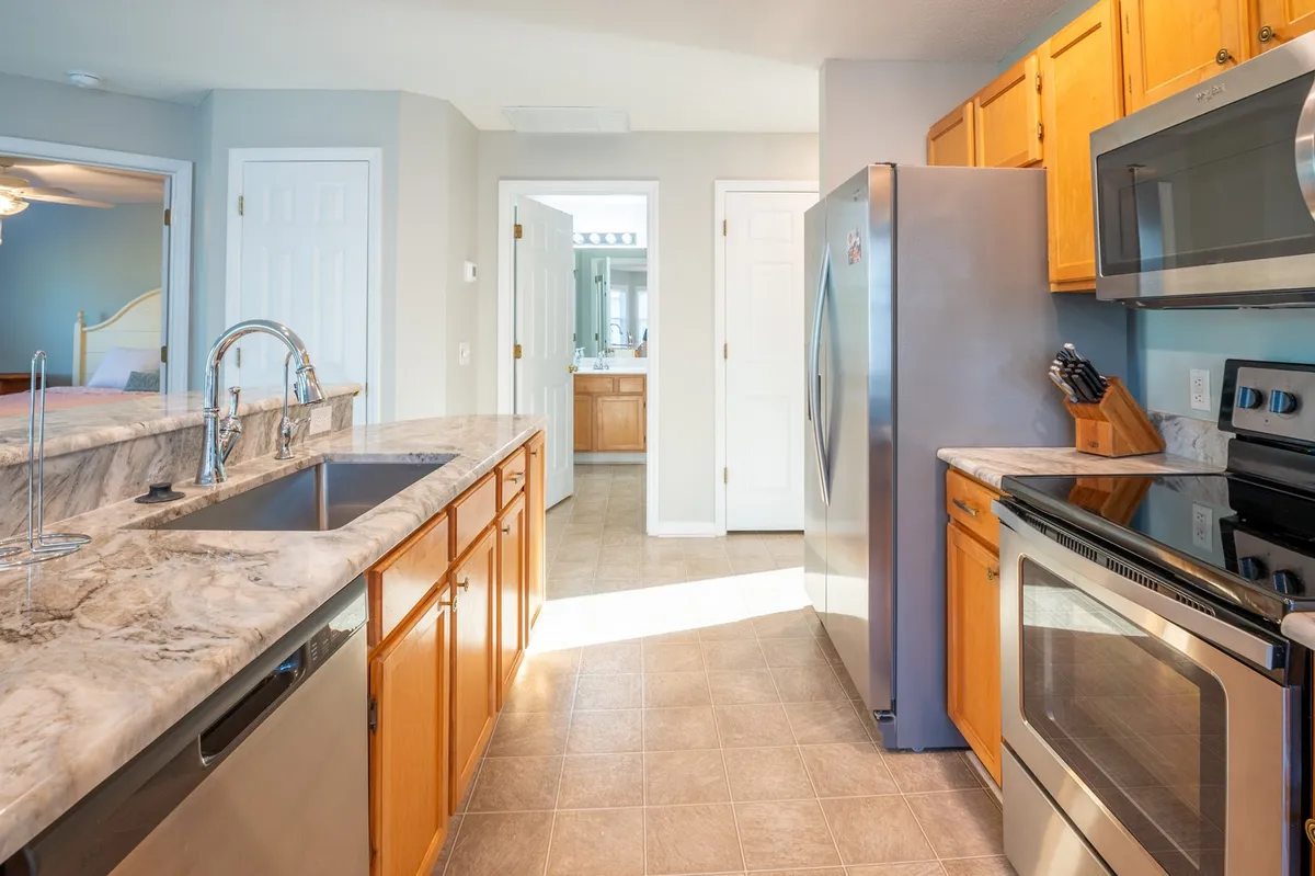 A closer view of the kitchen island reveals its granite countertop, gleaming stainless steel appliances, and spacious layout—ideal for meal prep or entertaining. The space exudes both style and functionality, with tasteful decor enhancing the inviting vibe.