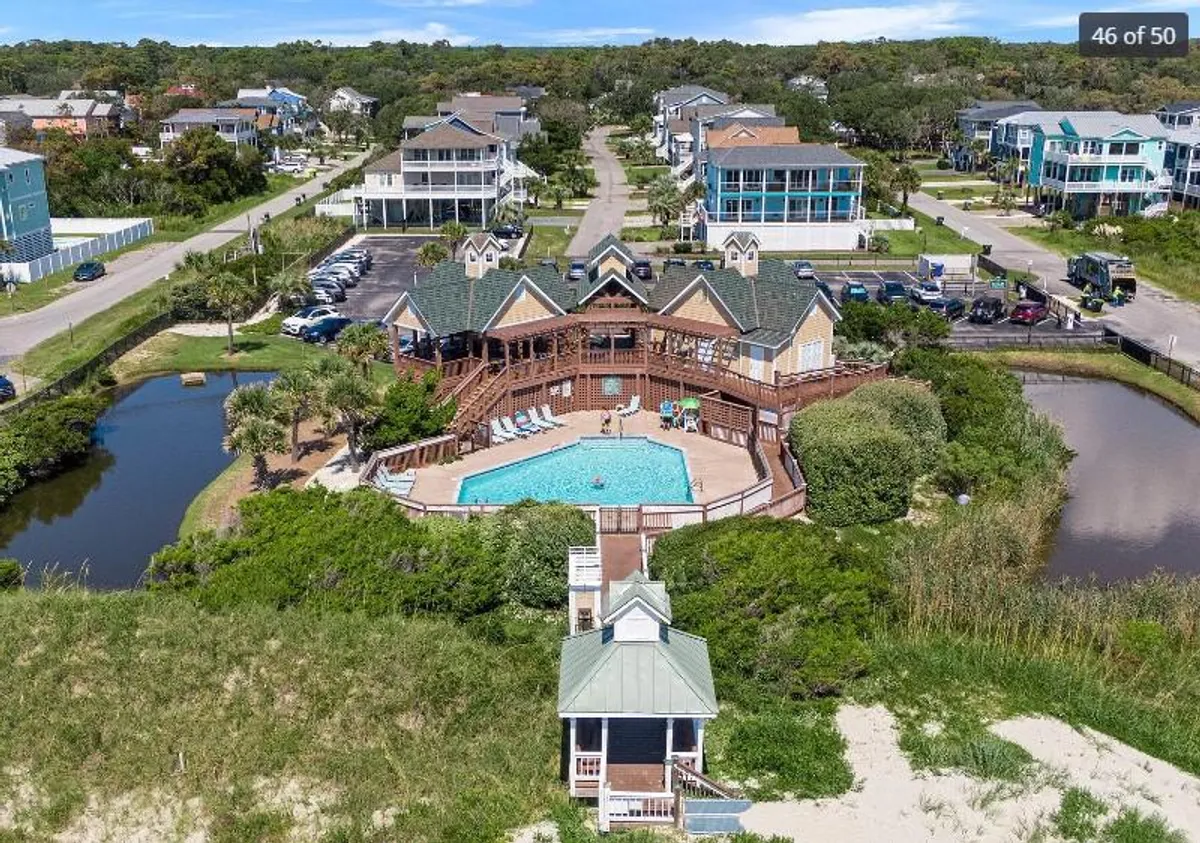 A spacious swimming pool set amid lush greenery, with a deck area perfect for lounging. The pool area is surrounded by natural landscaping and adjacent water bodies, evoking a resort-like atmosphere ideal for both relaxation and family fun.