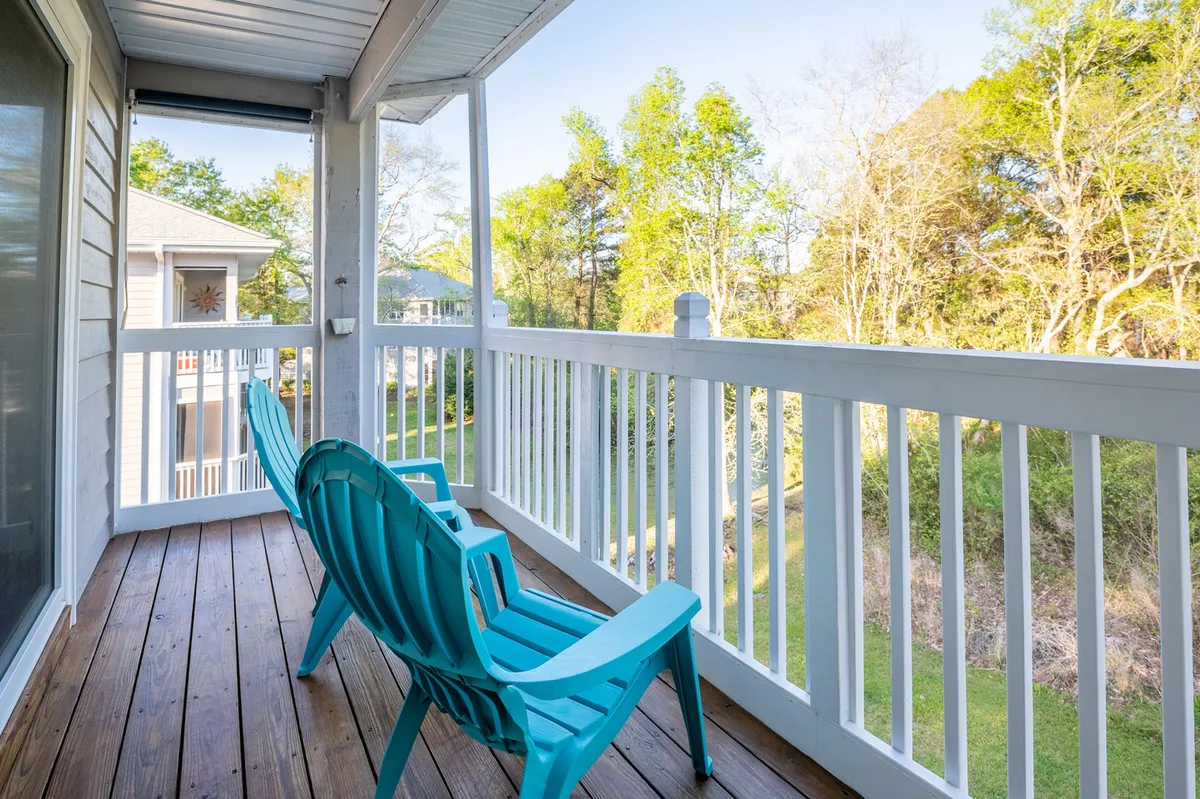 An inviting shot of a wooden deck featuring blue Adirondack chairs nestled among trees, creating a serene outdoor retreat. The space is perfect for enjoying morning coffee, conversations, or soaking in the sunrise.