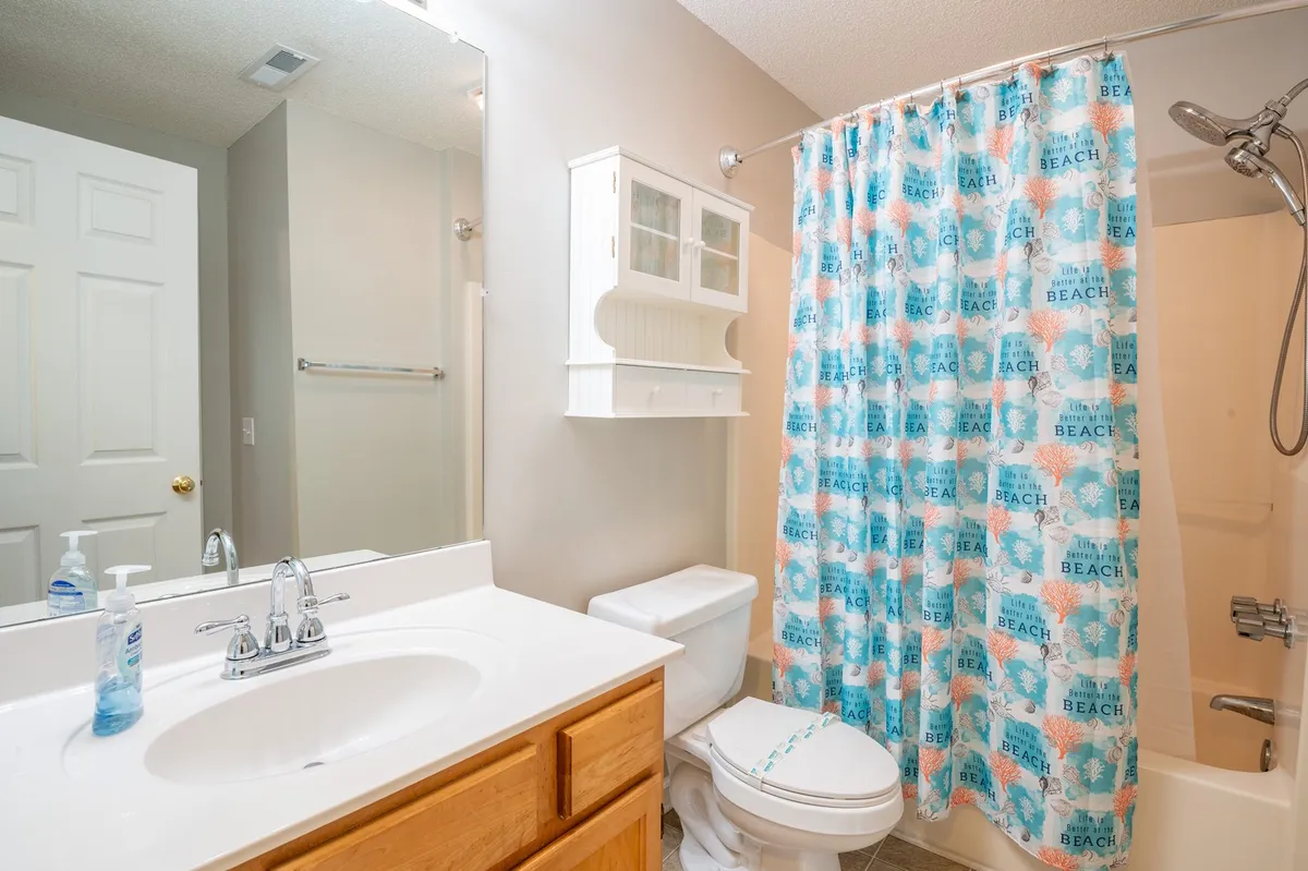 A well-appointed bathroom with a modern sink, mirror, shower curtain, and toilet. The clean, inviting space is ideal for personal grooming and relaxation, adding to the suite's convenience and comfort.