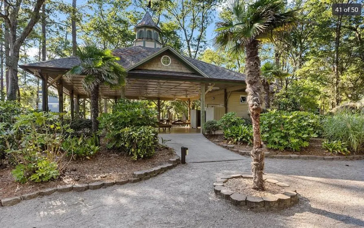 An exterior shot featuring a charming gazebo surrounded by palm trees and lush landscaping. The setting appears tranquil and inviting, perfect for gatherings, outdoor dining, or simply relaxing. The space reflects a resort-like atmosphere with ample greenery and an open-air vibe.