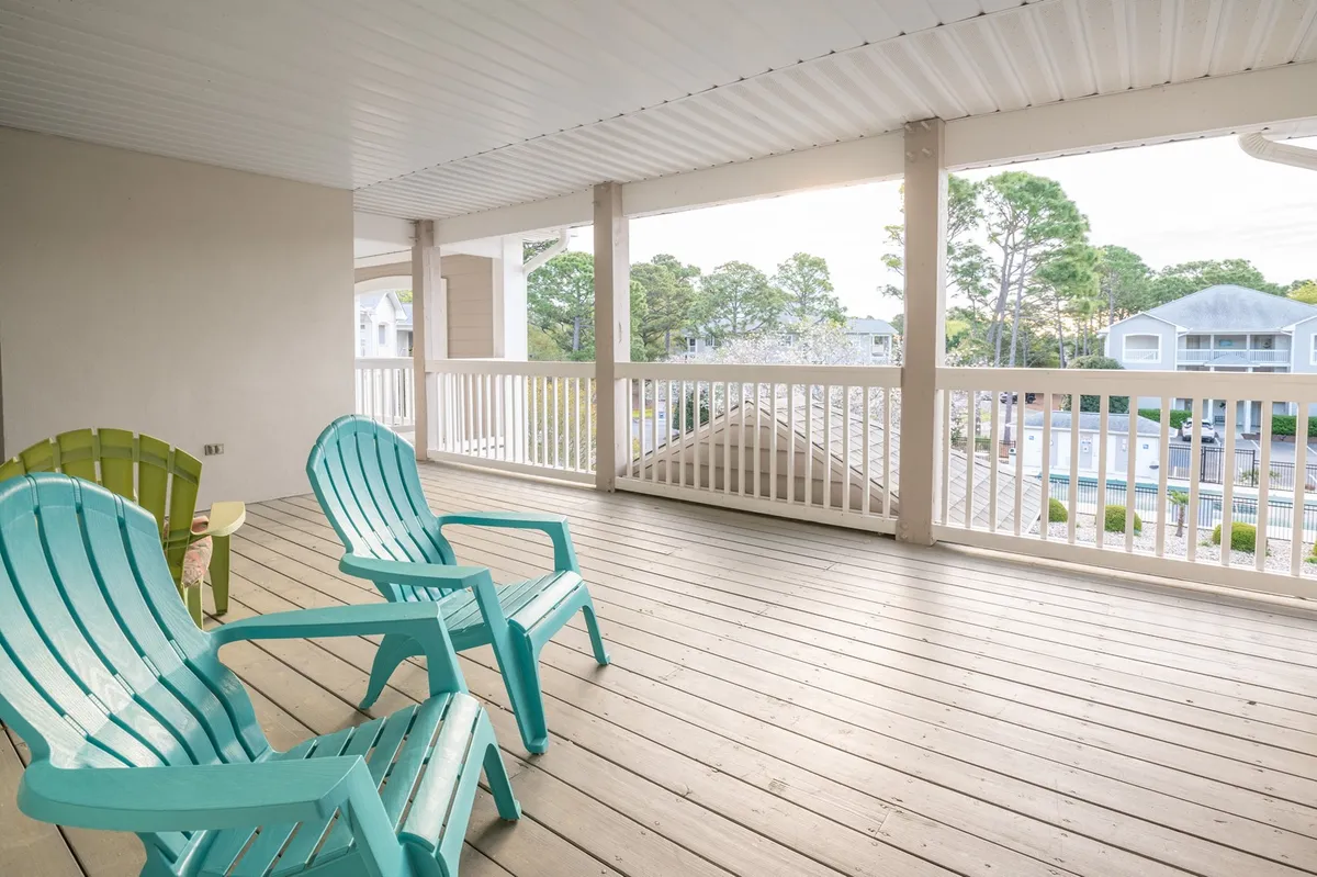 This image showcases a tranquil wooden deck furnished with turquoise chairs, surrounded by greenery. The outdoor setting is peaceful, ideal for morning coffee, reading, or simply enjoying the natural atmosphere. The deck emphasizes an affordable way to enjoy quality leisure time at the condo.